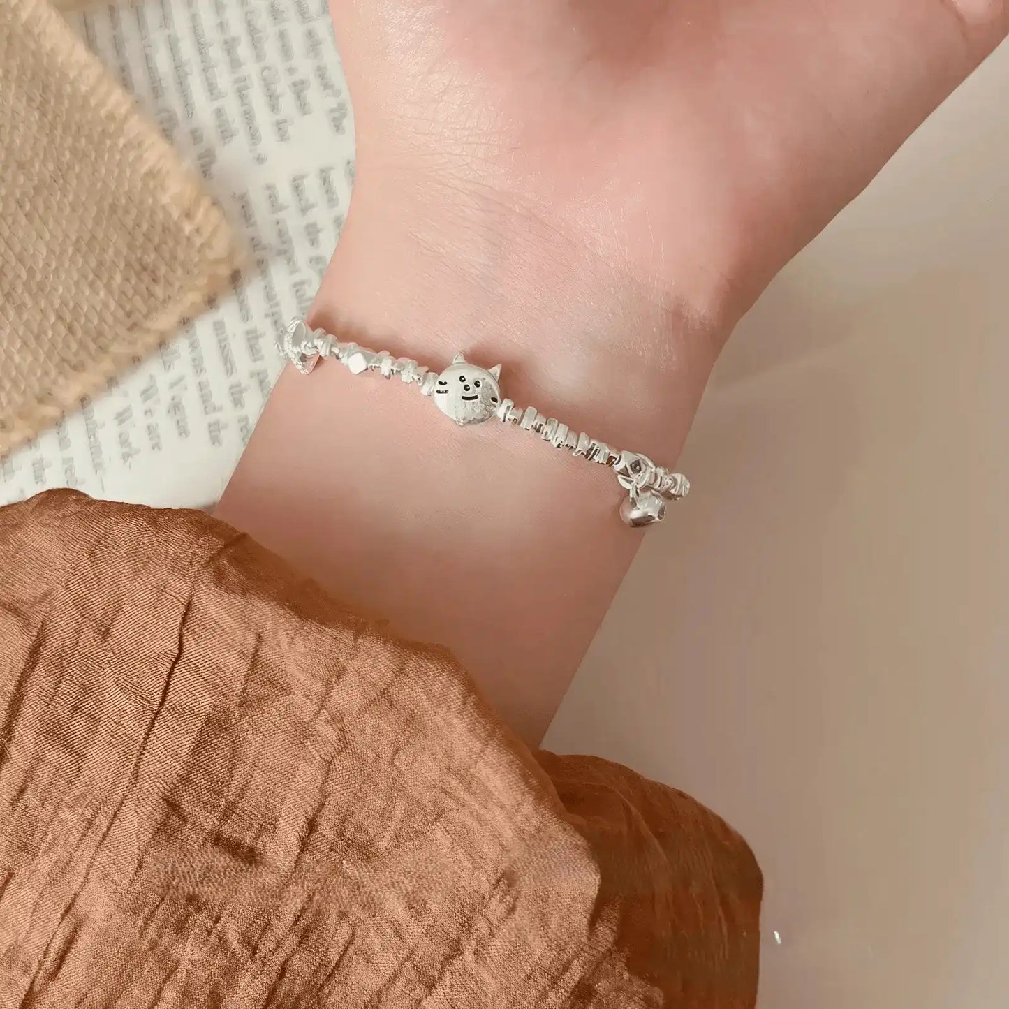 Kitten eating fish silver bracelet, worn on wrist with brown sleeve