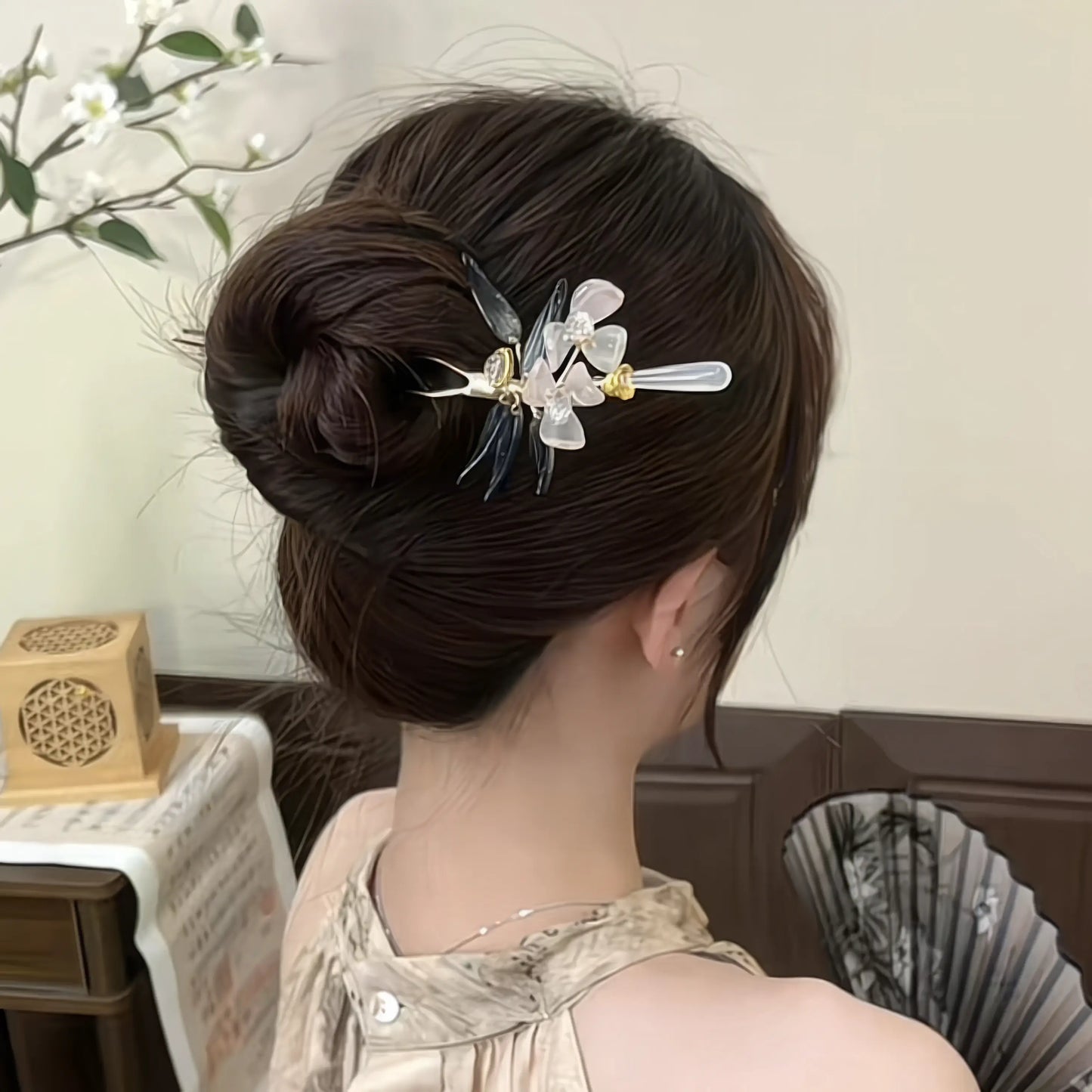 A woman with a bun wearing the magnolia hairpin, in a light-colored dress