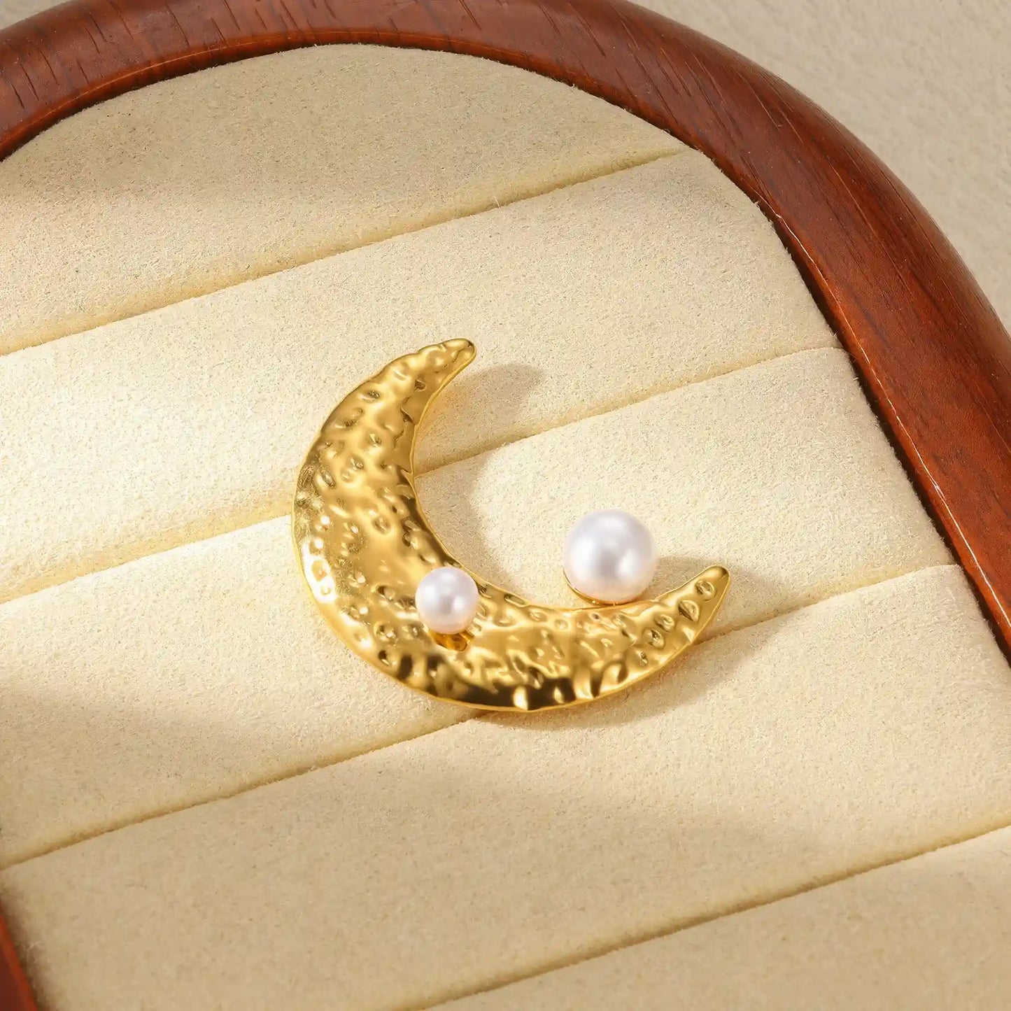 Gold moon - shaped brooch with pearls, placed on jewelry tray, showcasing style