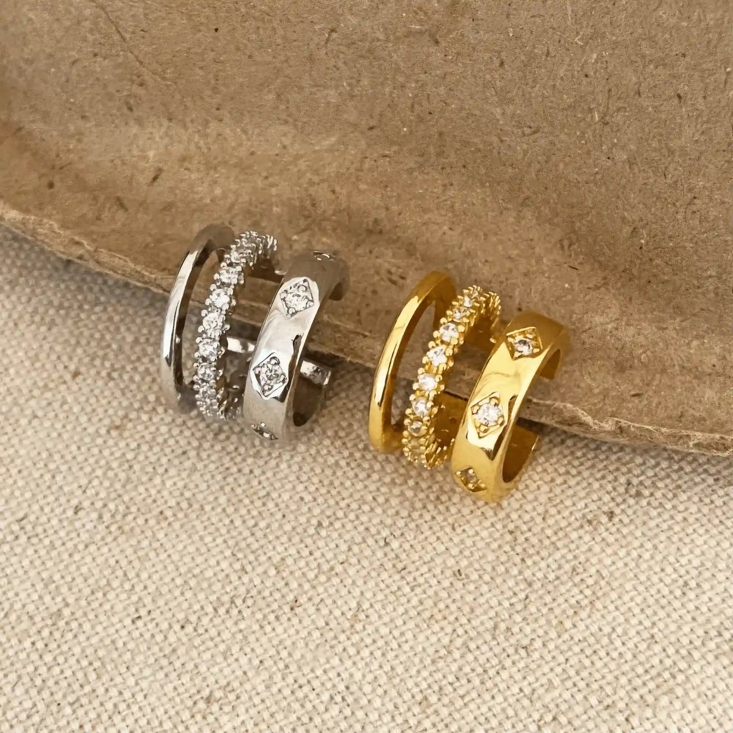 Mixed gold and silver multi - layer zircon ear cuffs displayed on a beige surface, emphasizing variety