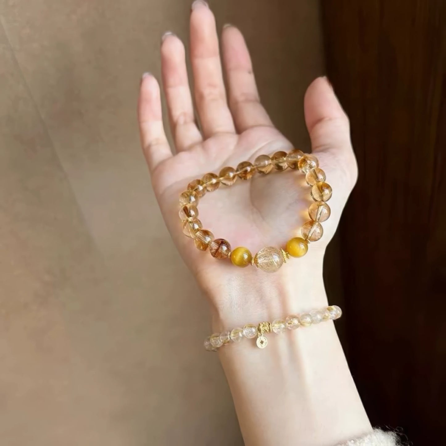 Hand holding natural stone citrine rutilated quartz bracelet, showcasing design details