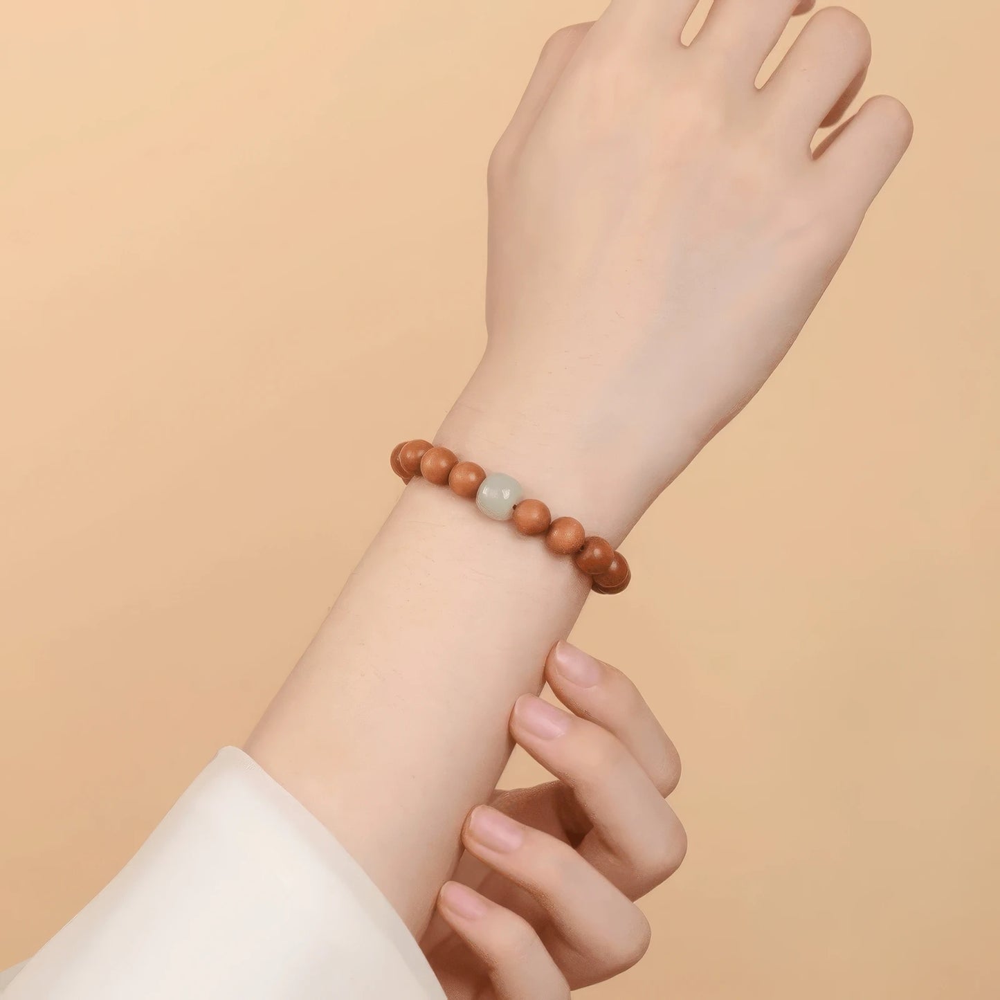 Old peach wood bracelet with green accent bead, worn on wrist, highlighting elegance
