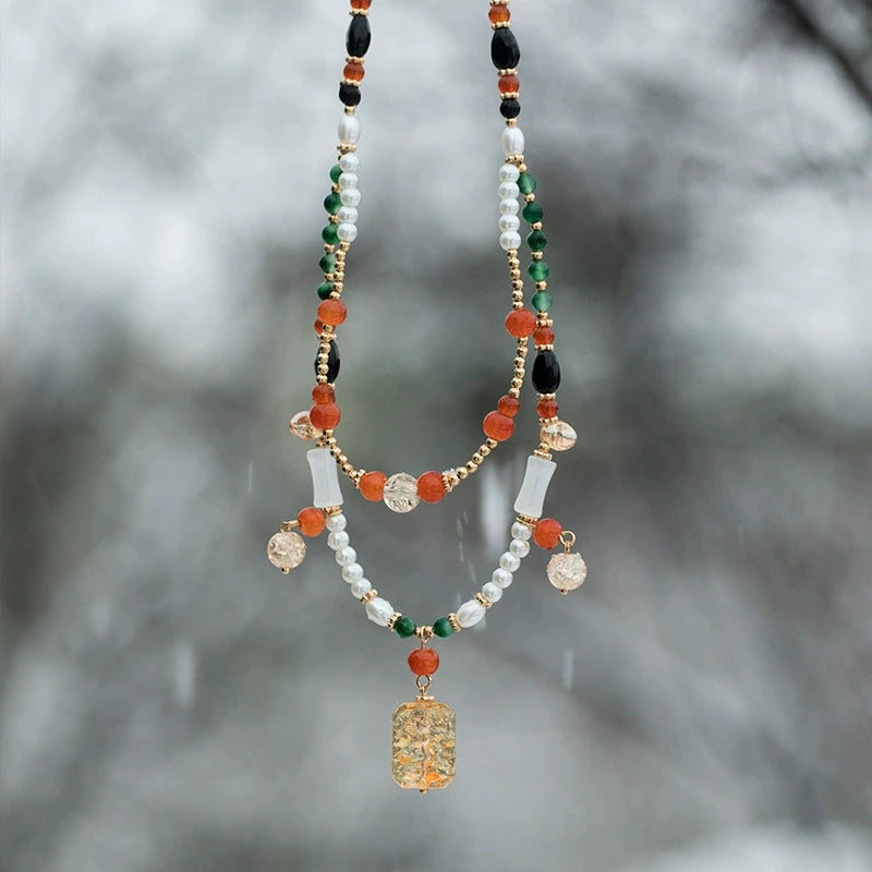 Orange flower pendant necklace with colorful beads, worn in a double - layer style, outdoor background