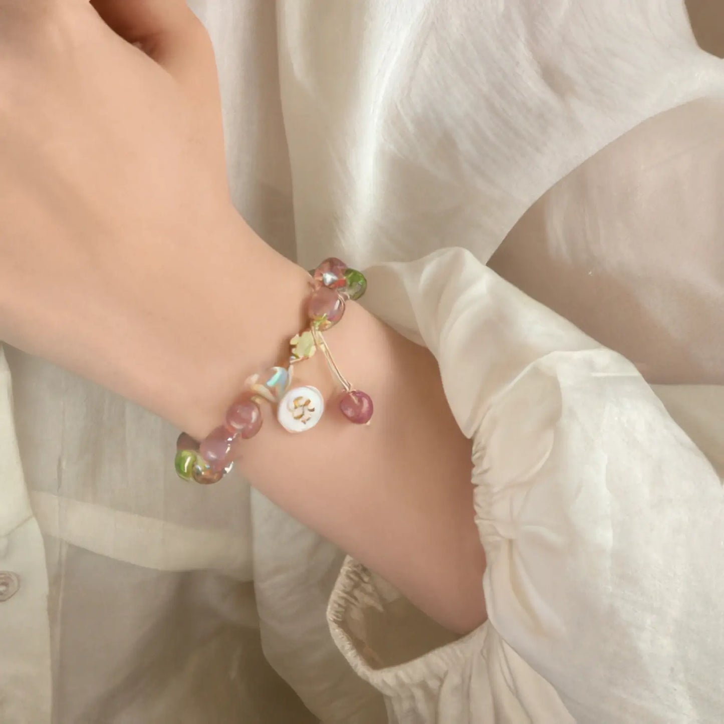 Peach blossom strawberry pink beaded bracelet worn on a wrist with white sleeve