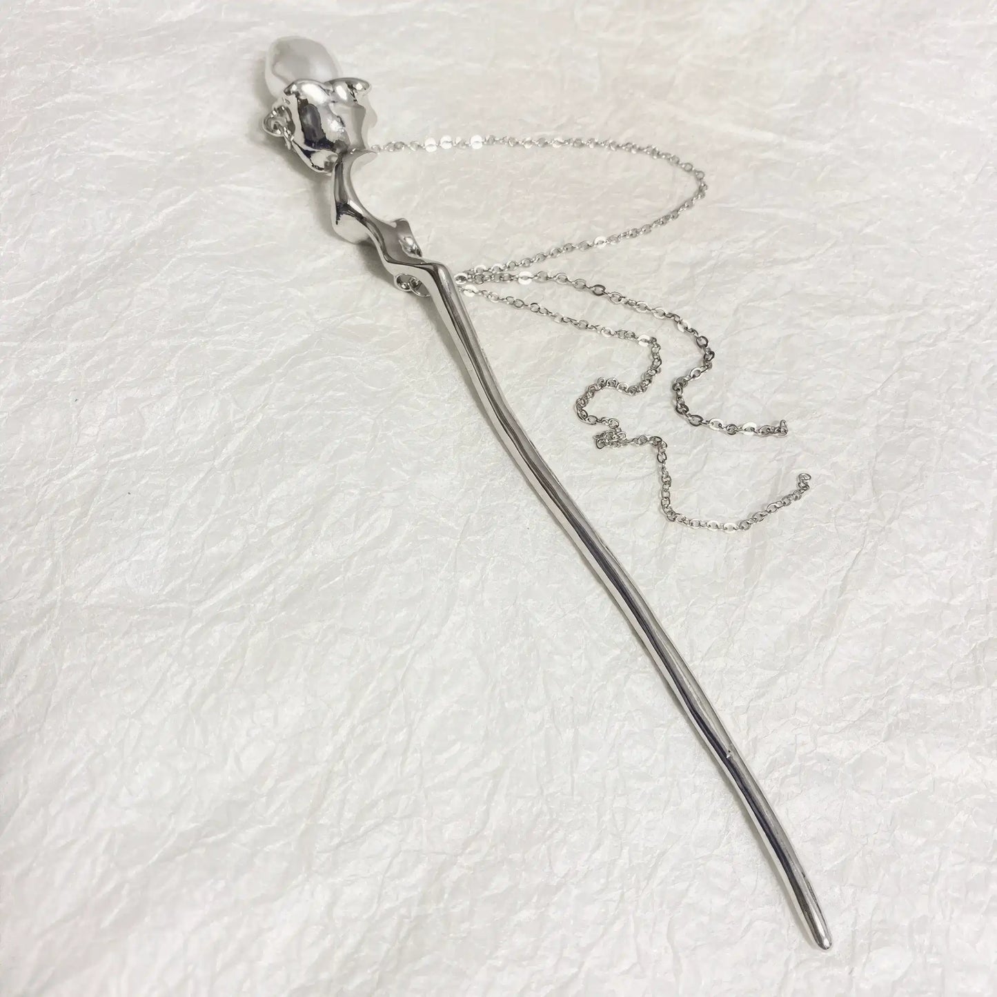 Silver pearl chain hairpin isolated on white textured surface, side view