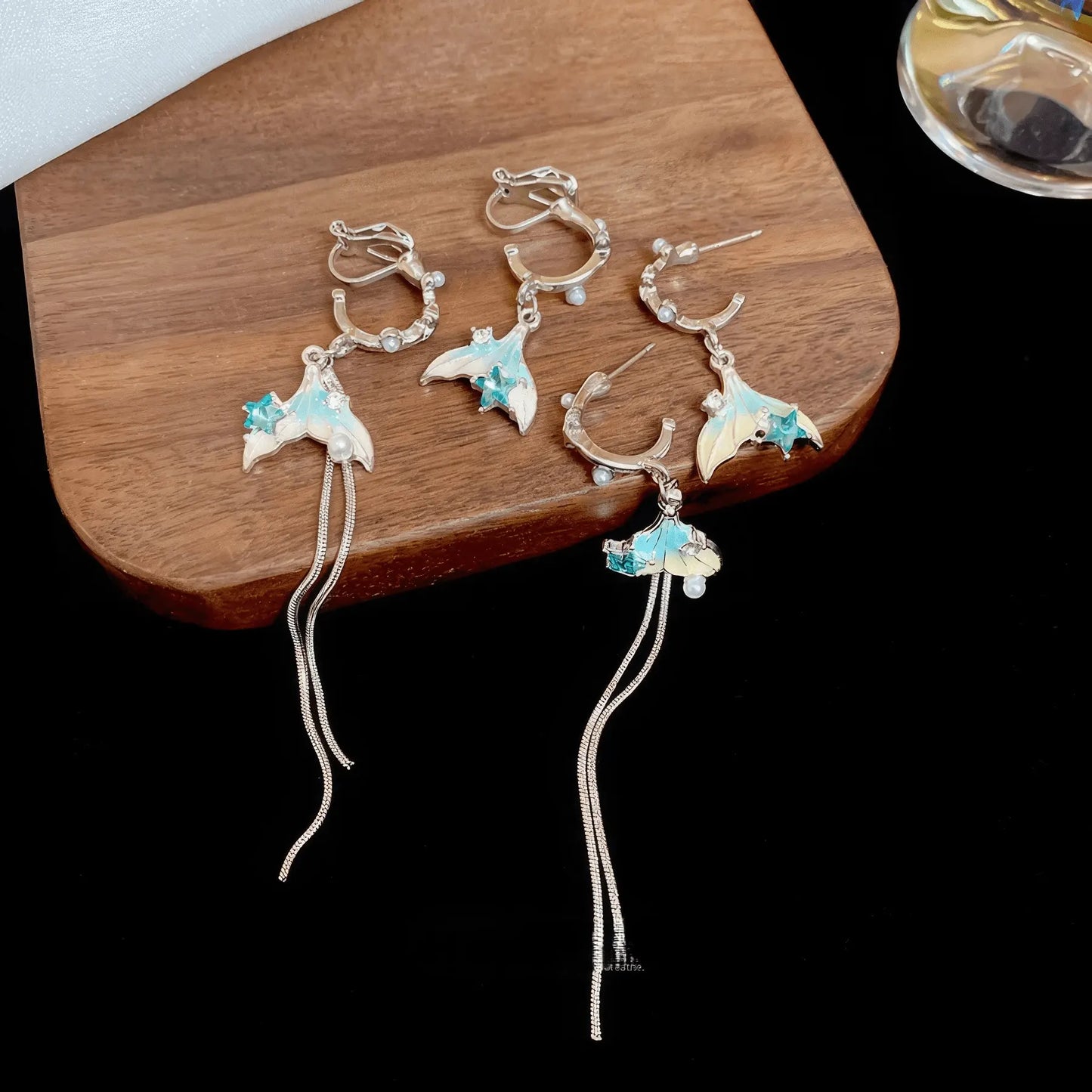 Pearl fish tail tassel earrings set, silver - tone, displayed on wood and black pad