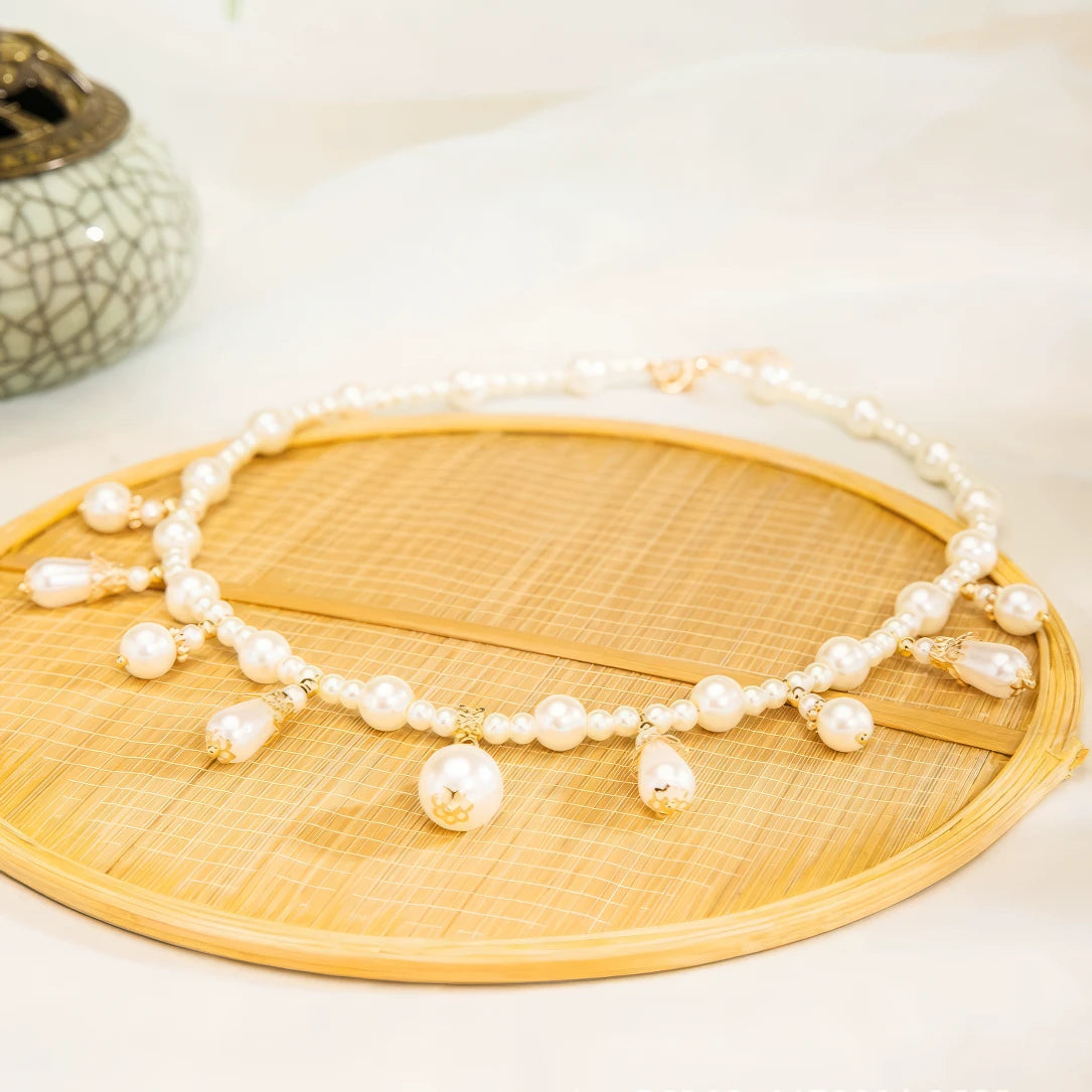 Pearl necklace with gold details, displayed on bamboo plate, light background