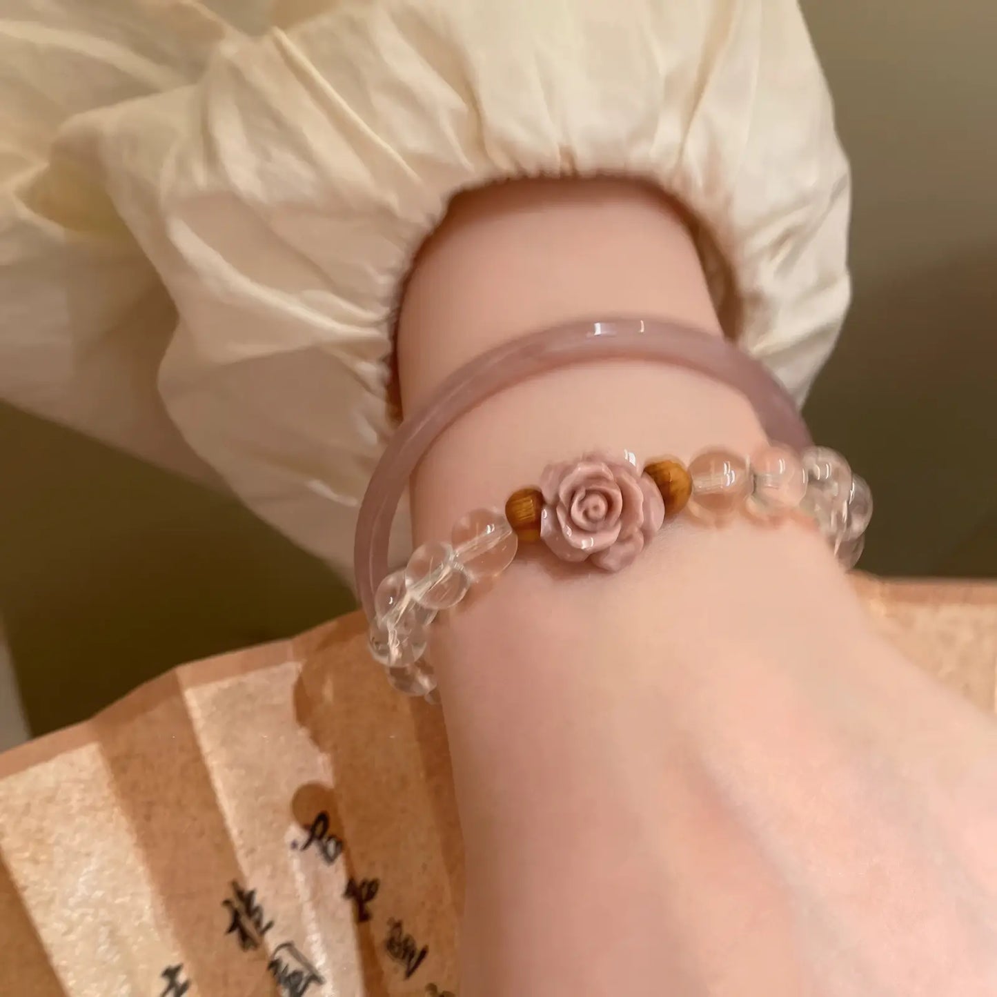 Pink mist rose flower beaded bangle worn on a wrist with white sleeve