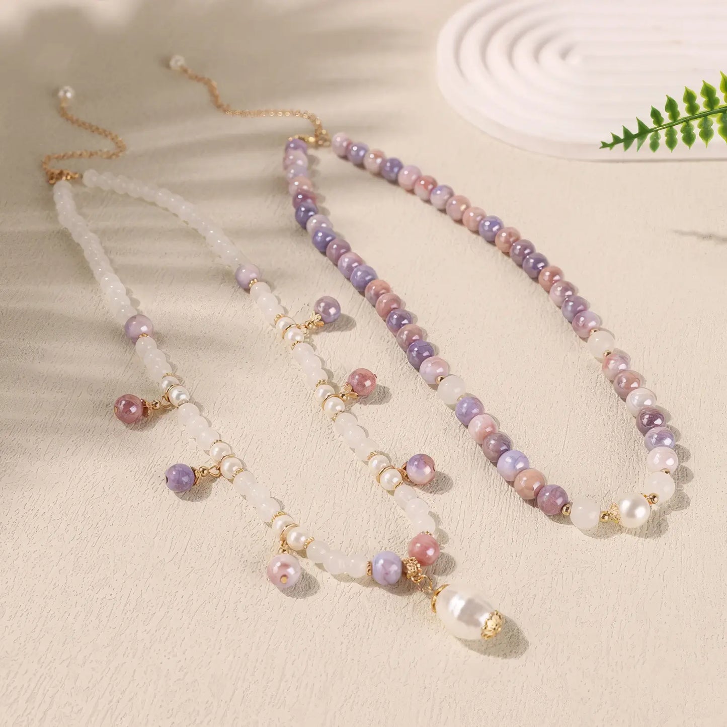 Side view of purple bead and pearl necklace on light background