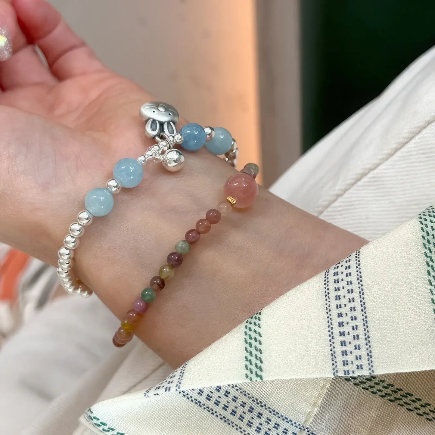 Rainbow tourmaline beaded bracelet worn with other bracelets on a wrist