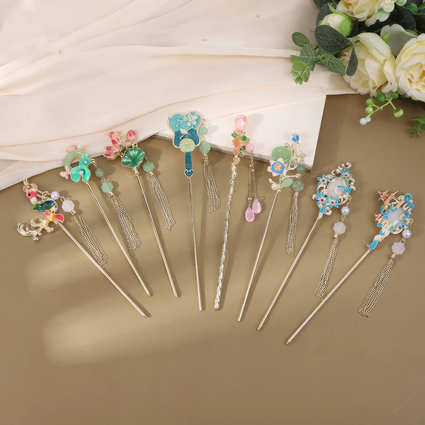 Set of Shuiweipei hairpins with various floral, bead and tassel designs, brown background with white fabric and flowers