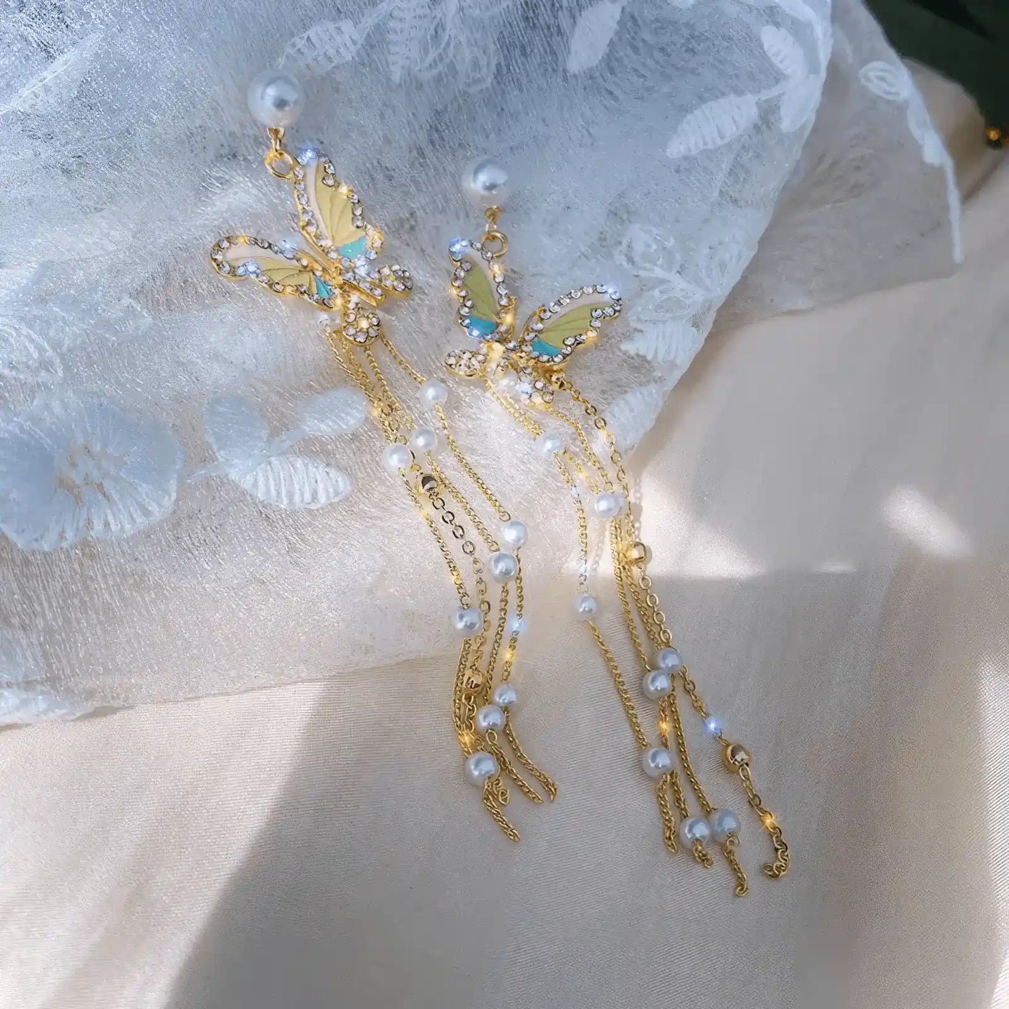 Tassel butterfly earrings with pearls displayed on light - colored fabric