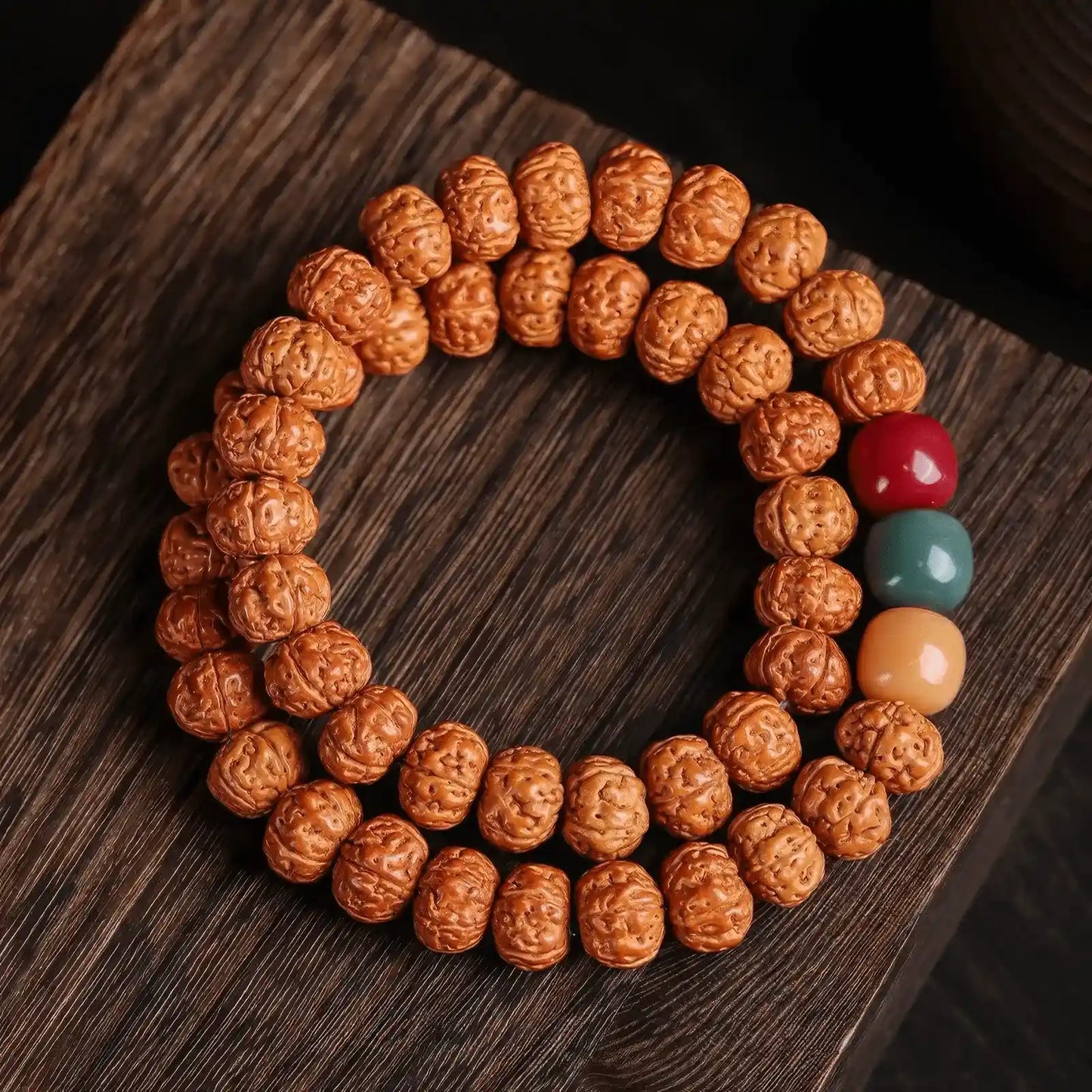 Double - strand vajra bodhi bracelet with multi - colored accent beads, on wooden surface