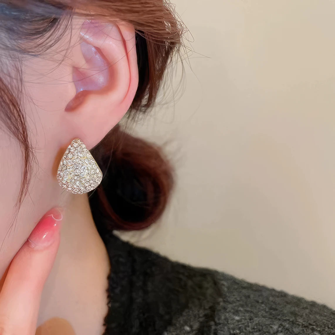 Gold water - drop diamond hoop earrings worn on ear, showcasing elegant style