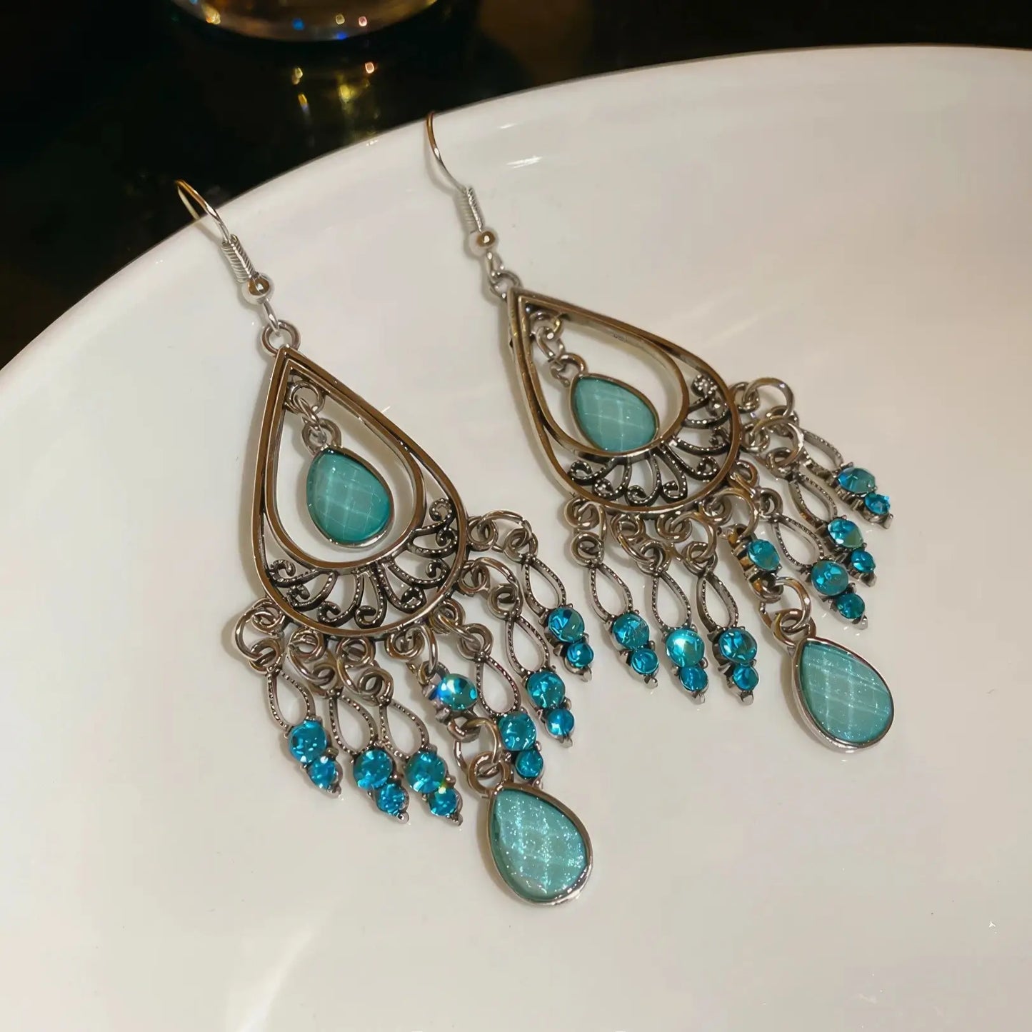 Water drop tassel earrings, blue stones with silver - tone filigree, displayed on white plate
