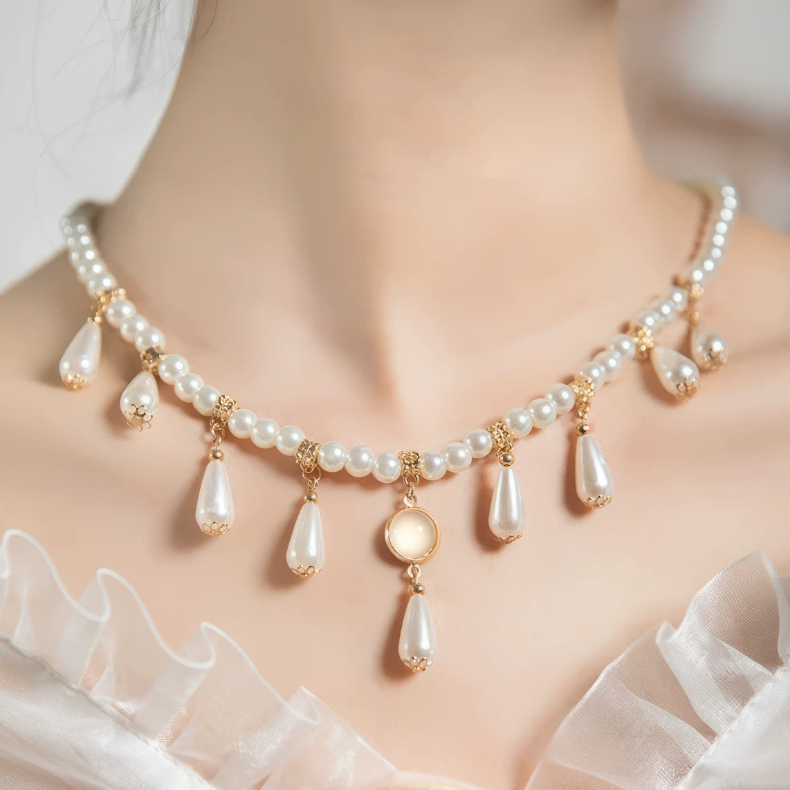 Woman wearing white water drop necklace with pearls and gold details, white ruffled clothing