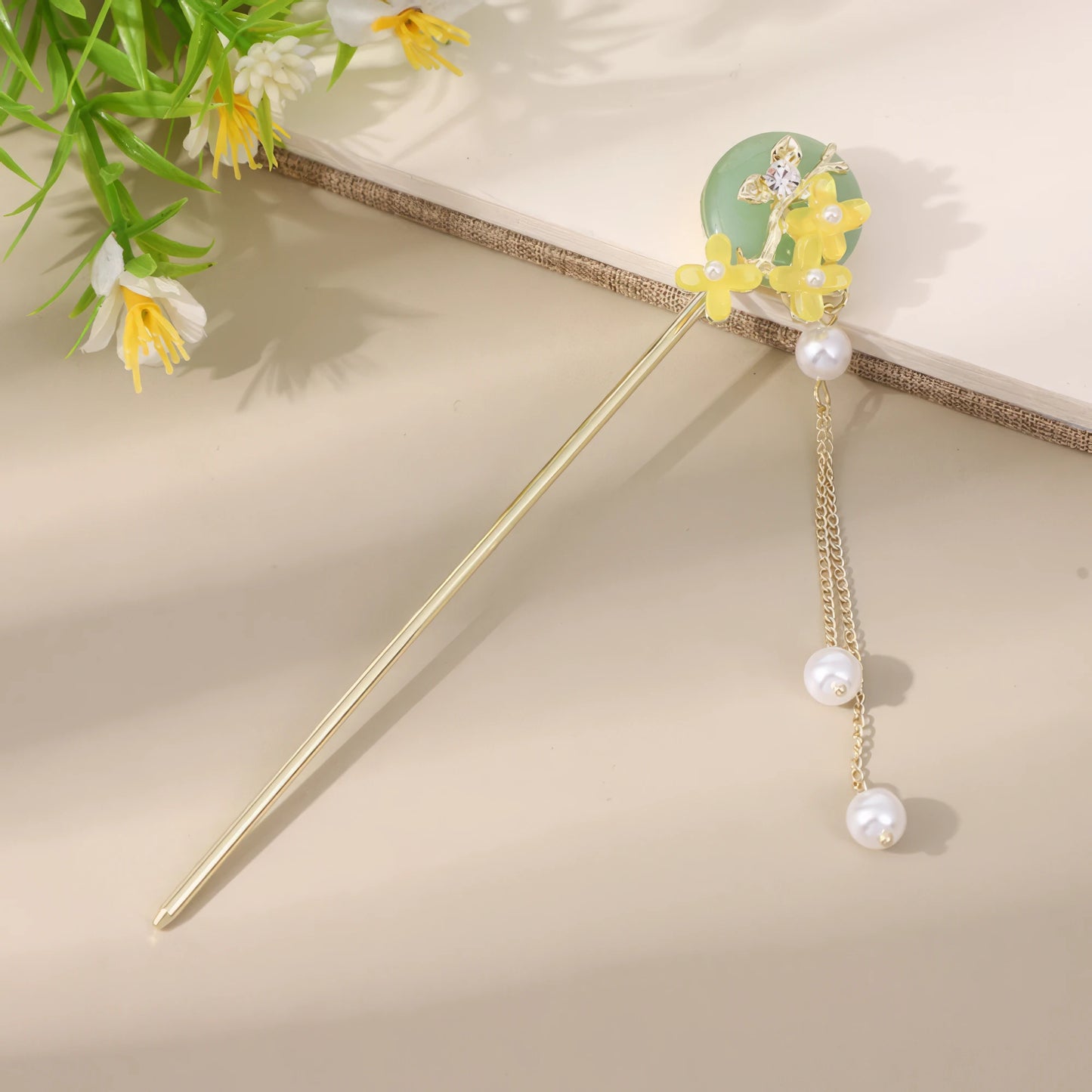 Xintingwang gold hairpin with green jade and yellow flower, pearl tassel on beige background with greenery
