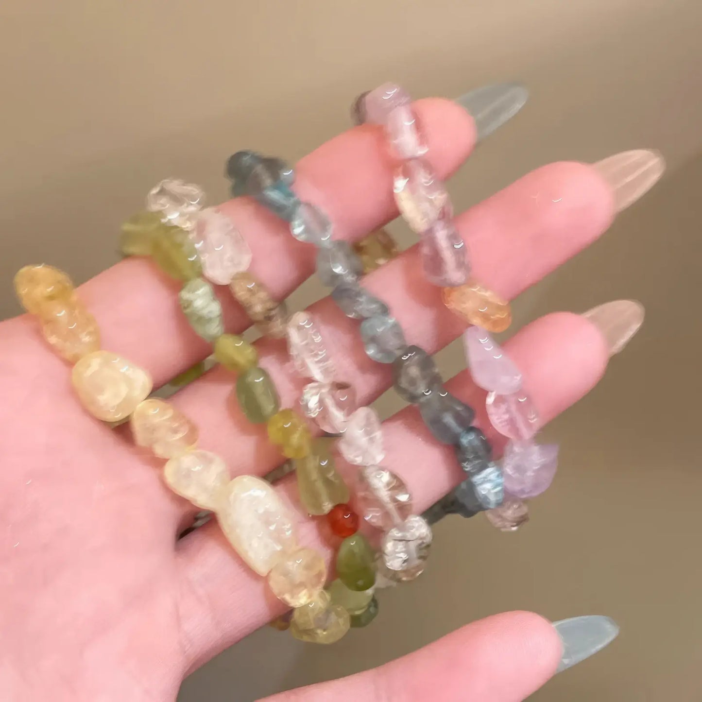 Hand holding multiple yellow beaded stretch bracelets with various stones