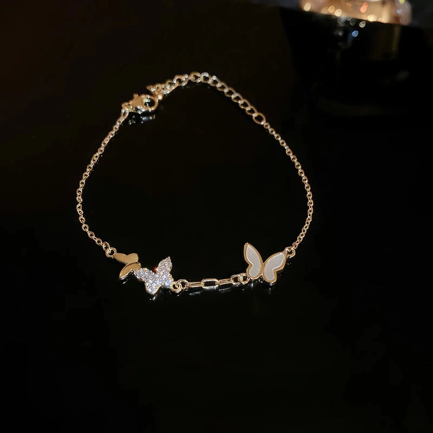 Zircon butterfly bracelet, gold chain with sparkling details, showcased on black background