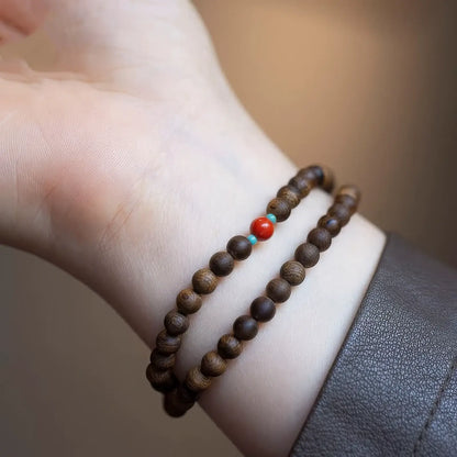 Agarwood double - layer bracelet worn on wrist, with a dark - colored sleeve.