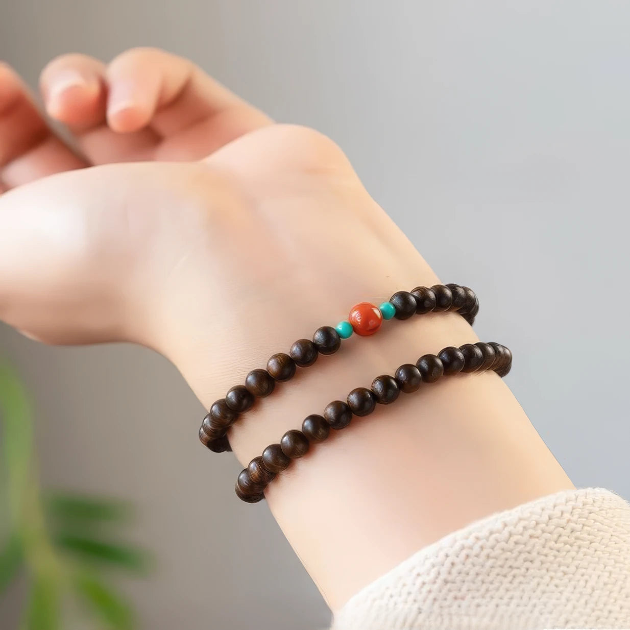 Agarwood double - layer bracelet worn on wrist, with a light - colored sleeve.
