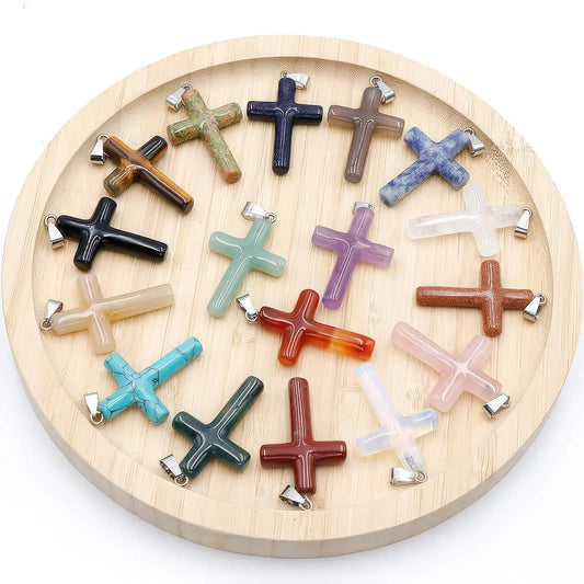 Set of various agate semi - precious stone cross pendants displayed on a wooden circular tray.