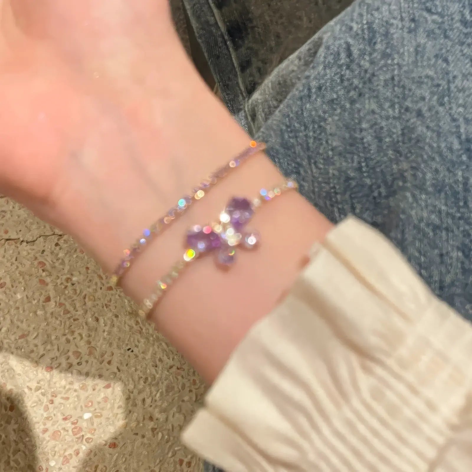  Amethyst butterfly bracelet worn on wrist, with a light - colored sleeve.