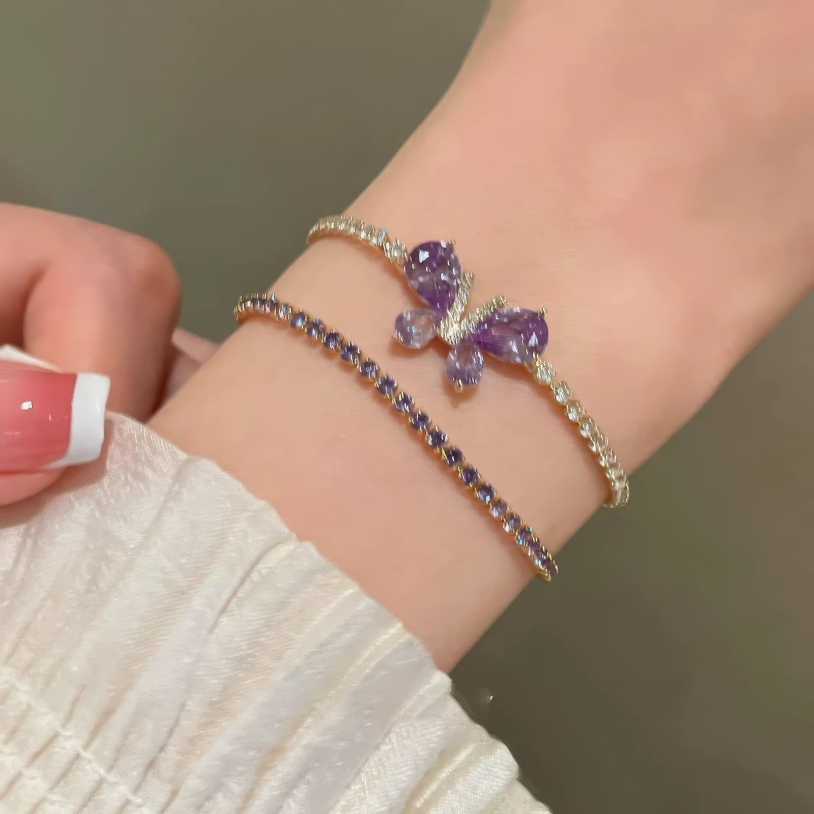 Amethyst butterfly bracelet being adjusted on wrist, paired with another bracelet.