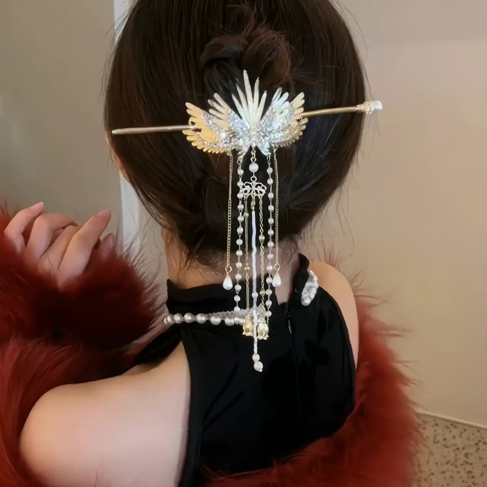 Golden wing pearl tassel hairpin used to decorate low bun hairstyle, with long cascading tassels adding romantic vintage charm.