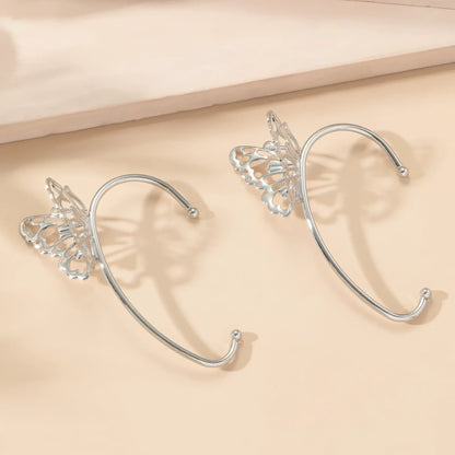 Pair of butterfly - style ear cuffs placed on a light - colored surface.