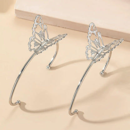 Pair of butterfly - style ear cuffs placed on a light - colored surface, showcasing detailed butterfly wings.