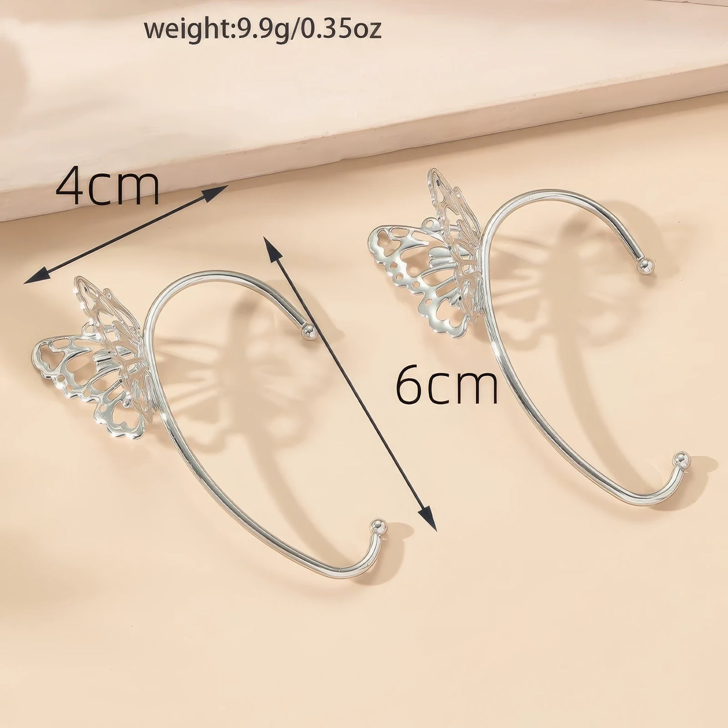  Butterfly - style ear cuff with size and weight details, placed on a light - colored surface.