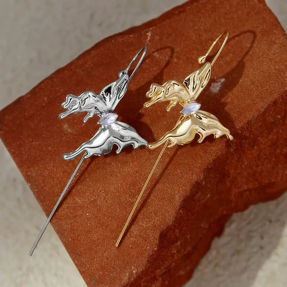  Pair of butterfly ear cuffs (gold and silver) placed on a brown surface.