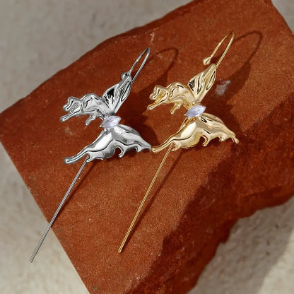  Pair of butterfly ear cuffs (gold and silver) placed on a brown surface.
