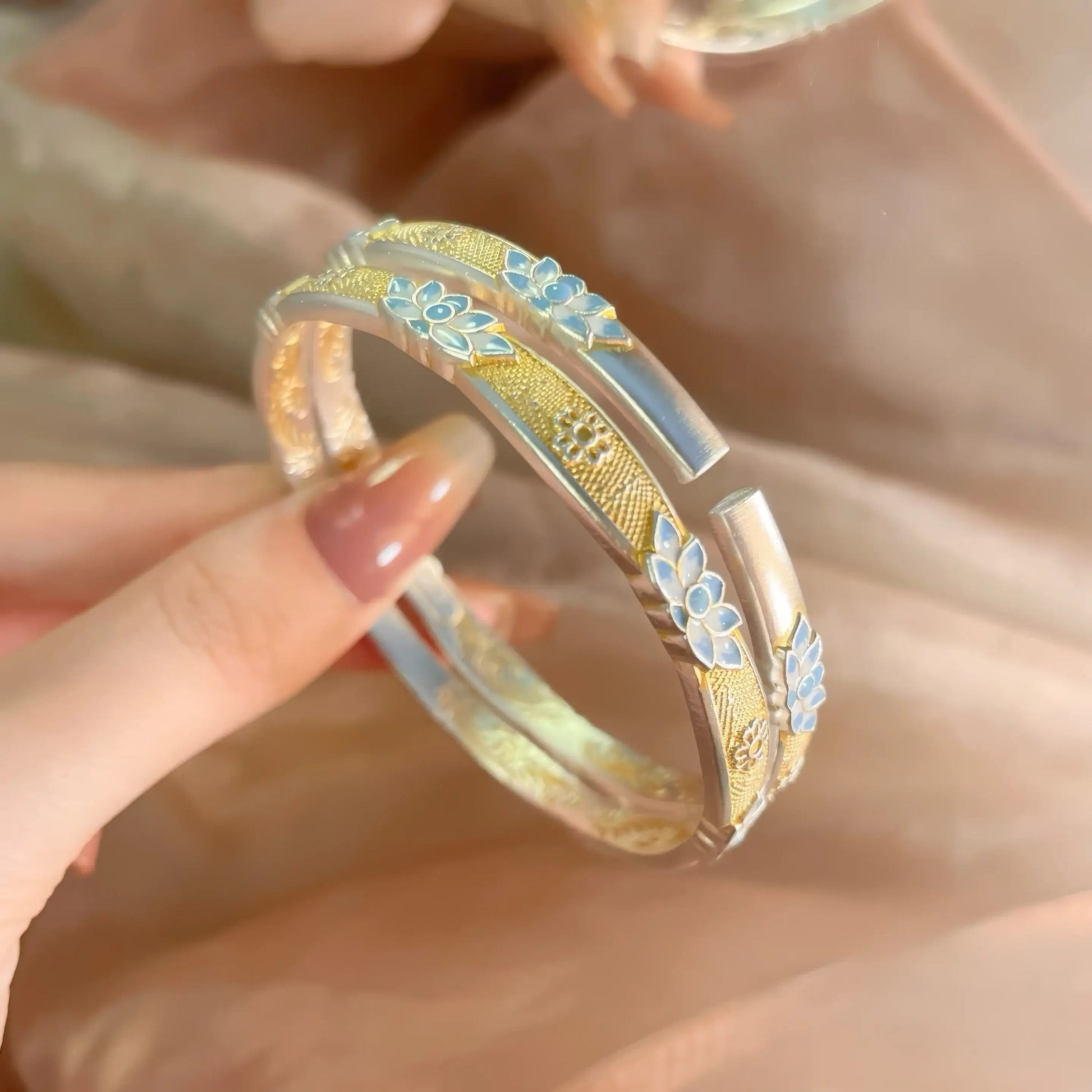 Close - up of enamel blue lotus bracelet, showing detailed blue lotus and gold - toned elements.