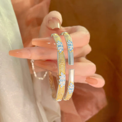 Enamel blue lotus bracelet held in hand, highlighting the intricate lotus pattern.
