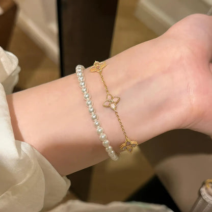 Flower petal pendant bracelet stacked with pearl bracelet on wrist.
