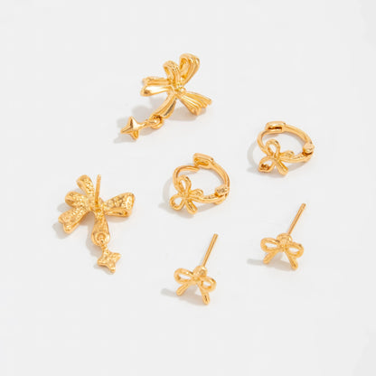 Set of gold bow tie stud earrings isolated on white background.