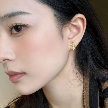 Gold butterfly stud earring worn on ear, showcasing elegant look