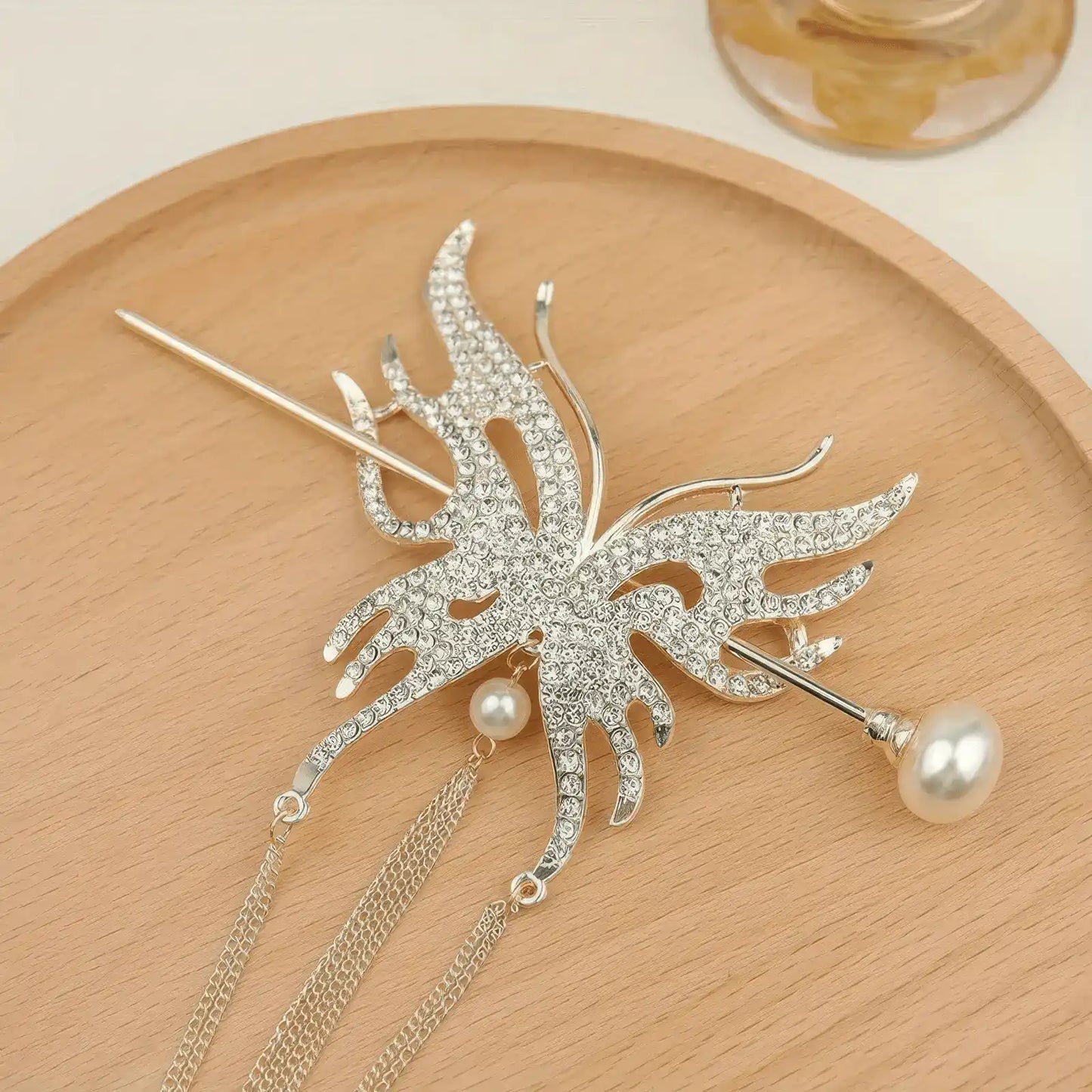 Gold-tone full rhinestone butterfly hair accessory set with long thin chain tassels, presented on wooden plate to highlight bright gold metal finish and crystal sparkle.