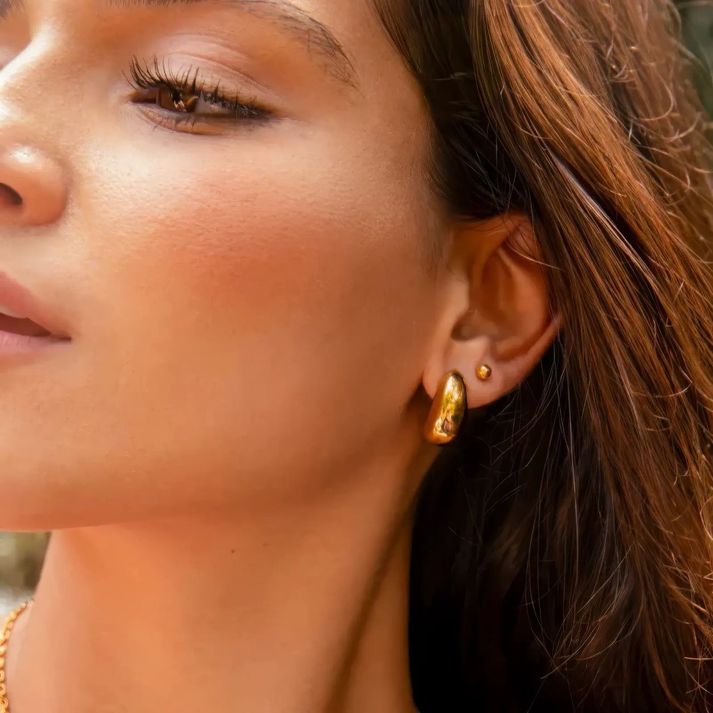 Gold teardrop heart stud earrings worn, showcasing elegant look on ear