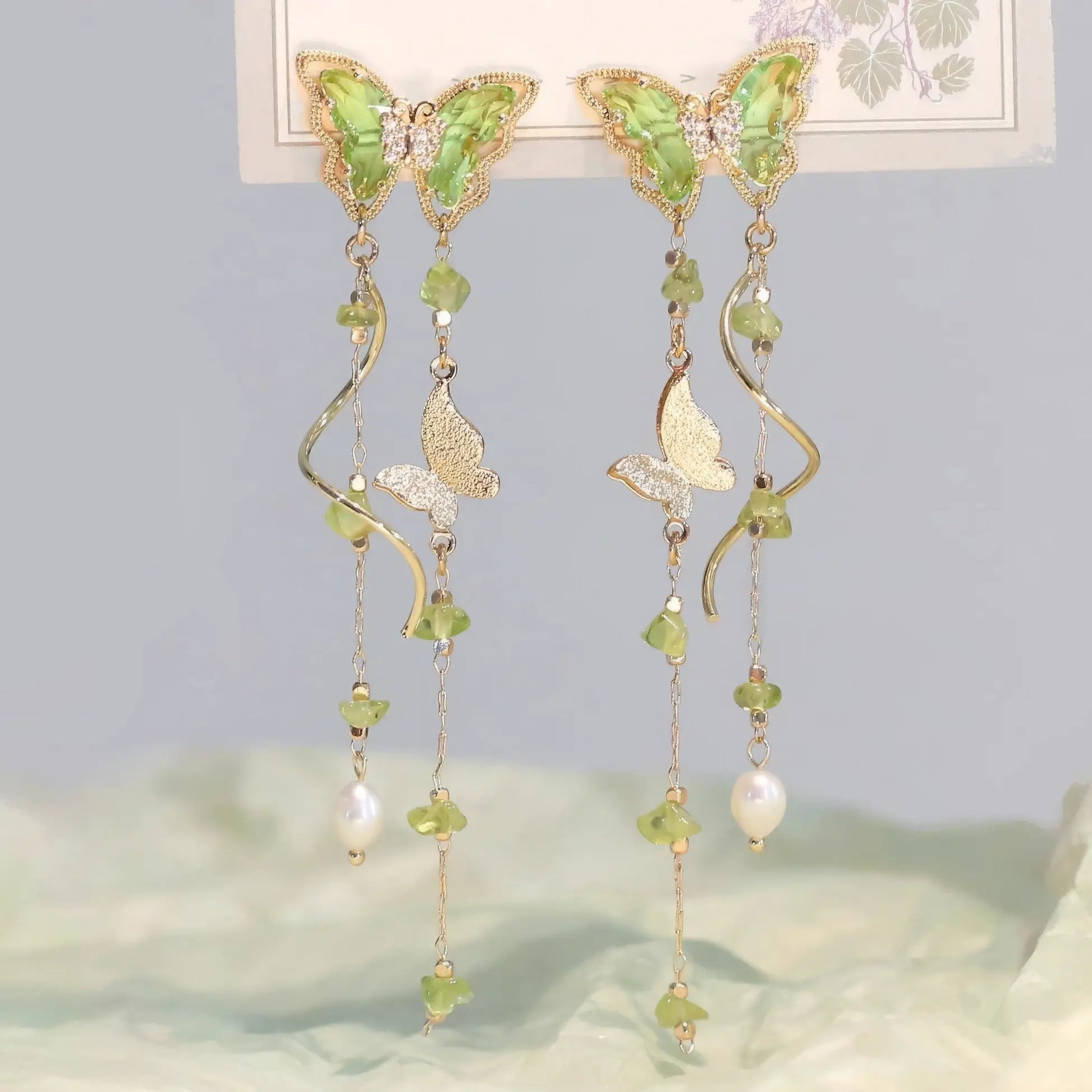 Green Wild Tea Butterfly Tassel Earrings displayed on a card, with a soft, nature - inspired background.