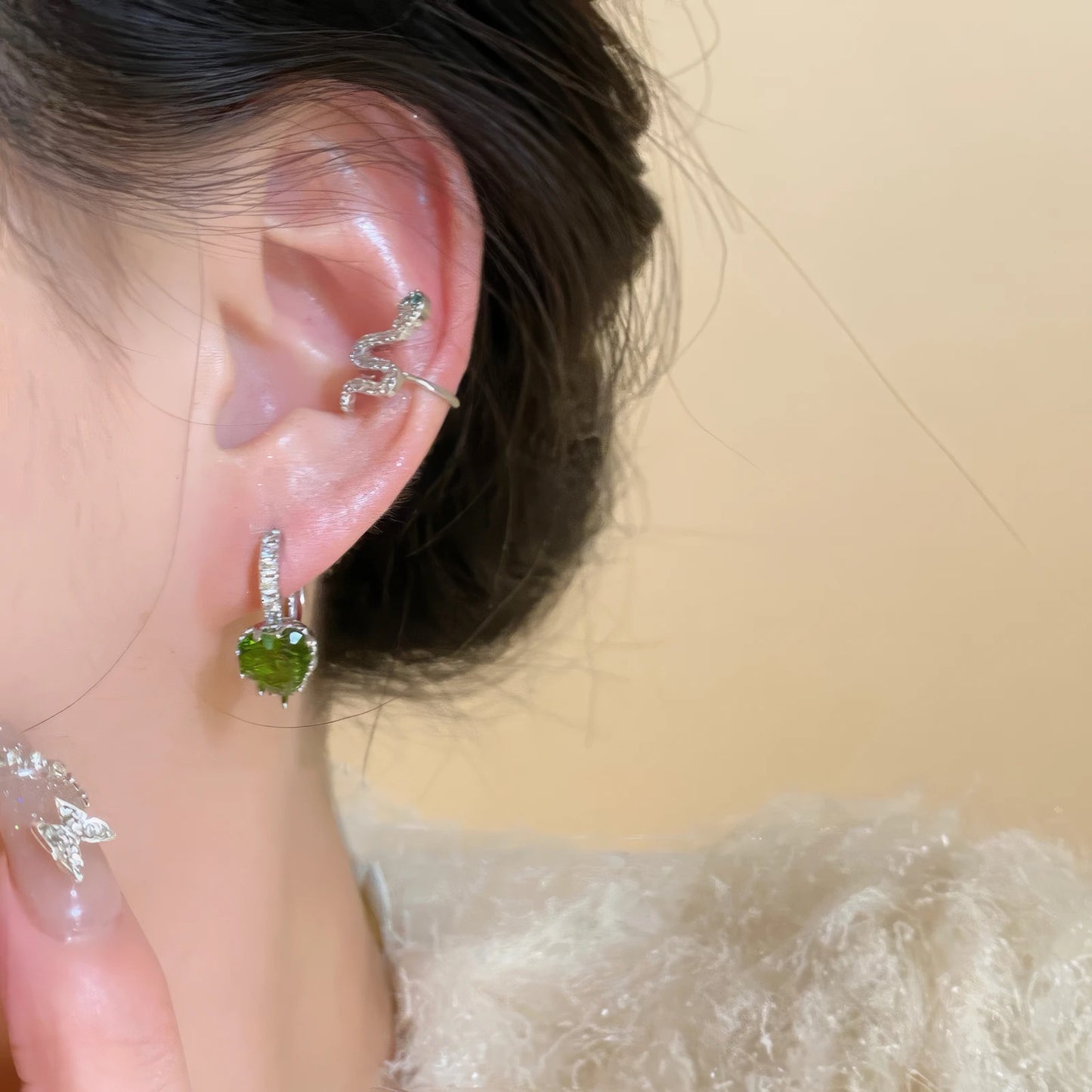 Green zircon snake - shaped stackable ear cuff worn on ear, showcasing the stacked design.
