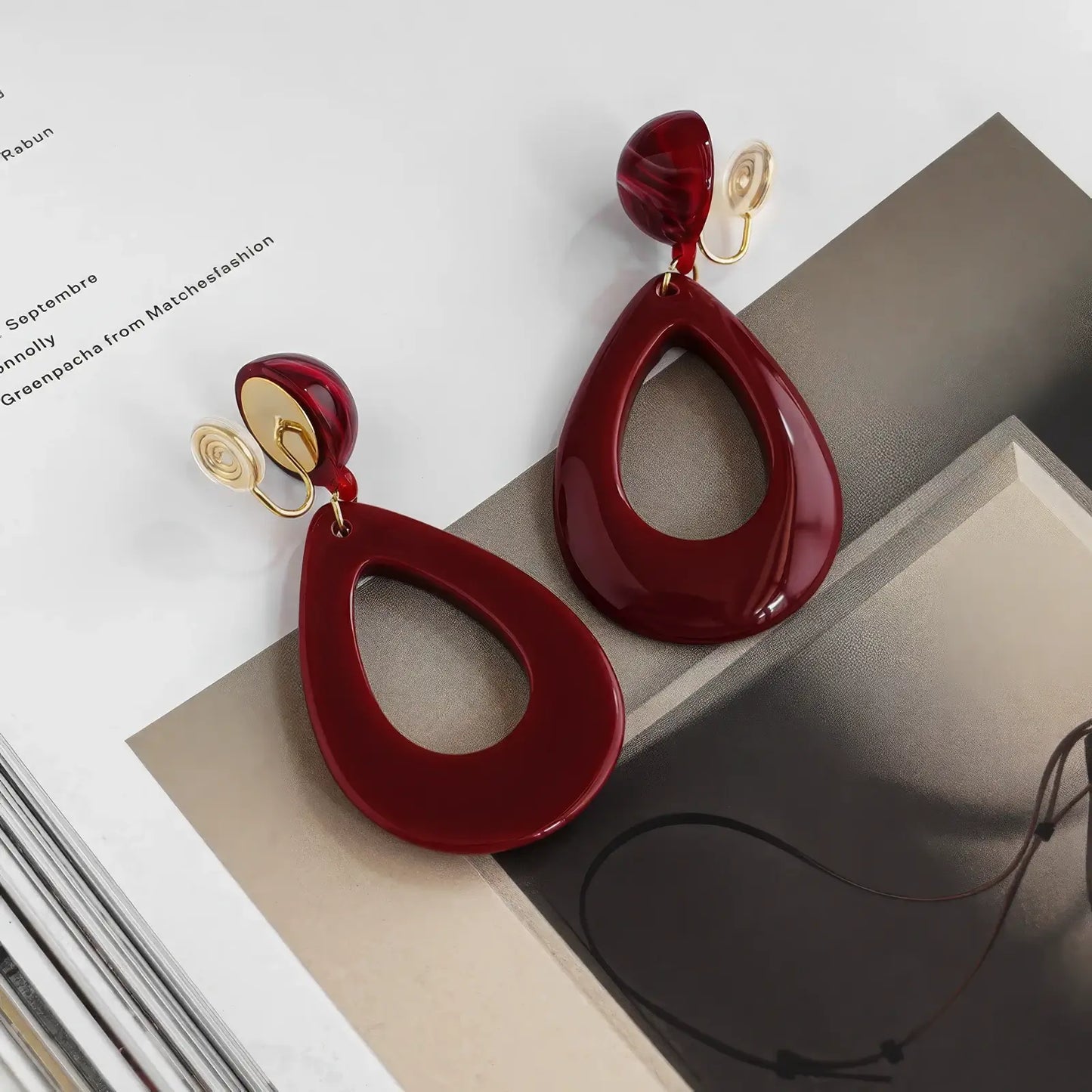  Hong Kong - style vintage burgundy ear clips placed on a magazine, highlighting the luxurious and glossy appearance of the ear clips.