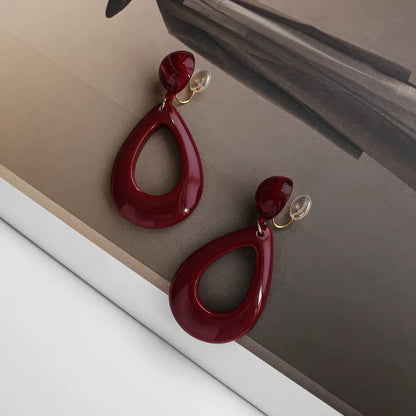  Hong Kong - style vintage burgundy ear clips shown on a magazine, showcasing the unique teardrop shape and rich burgundy color.