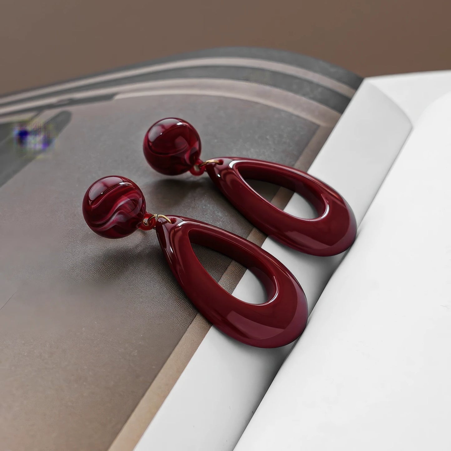  Hong Kong - style vintage burgundy ear clips displayed on a magazine, emphasizing the elegant and vintage - inspired design.
