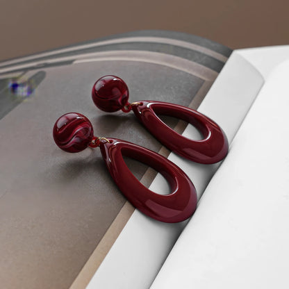  Hong Kong - style vintage burgundy ear clips displayed on a magazine, emphasizing the elegant and vintage - inspired design.

