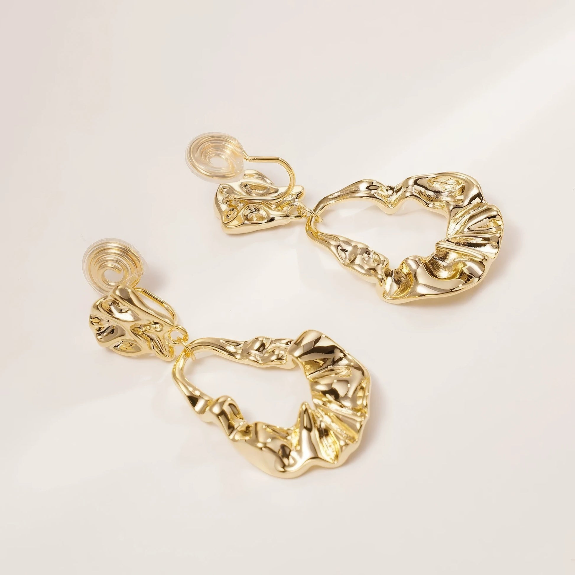 Pair of irregular - shaped gold earrings, showcasing textured, open - design drops, isolated on white background