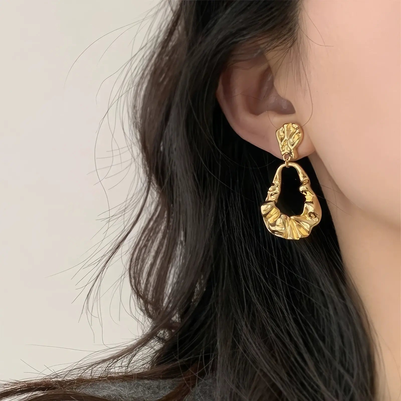  Irregular - shaped gold earrings worn, complementing dark hair, showcasing the bold and textured design