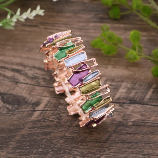  Irregular colorful enamel bracelet placed on a wooden surface, showcasing different color combinations.